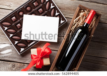 Ngày Valentine thiệp chúc mừng.  Rượu vang đỏ, hộp quà tặng và hộp chocolate trên bàn gỗ.  Top xem với không gian cho lời chúc mừng của bạn