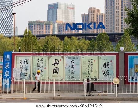 BEIJING, CHINA-MAY 20, 2017: A construction worker is seen at a side walk, Nokia sign as a background; NOKIA is a multinational communications and information technology company founded in 1865.