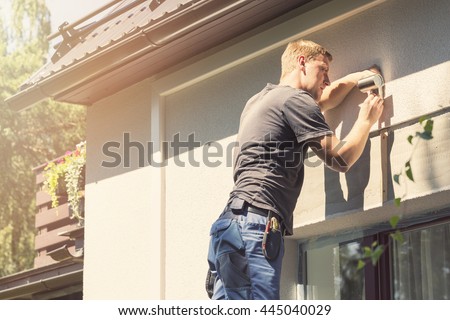 electrician installing lamp on house facade