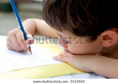 Young boy enjoying his handwriting homework, doing it outdoors in summer.