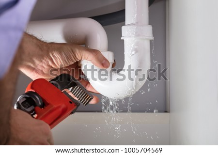 Close-up Of Male Plumber Fixing White Sink Pipe With Adjustable Wrench