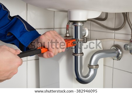 Close-up Of Male Plumber Repairing Sink In Bathroom