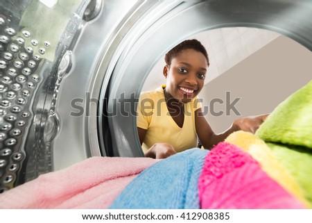 Young African Woman Putting Clothes Into Washing Machine At Home