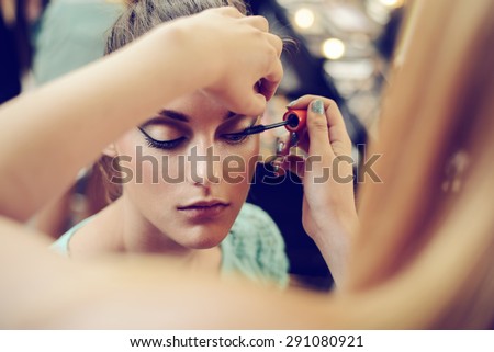 Make-up artist applying the mascara to model. Close up. 