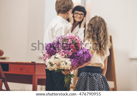 Boy and girl children give flowers as a school teacher in teacher's day
