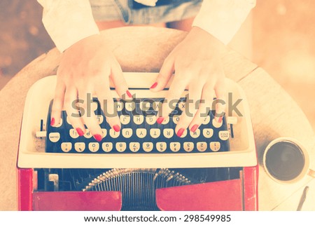 Girl at the table typing on a typewriter, vintage photo effect