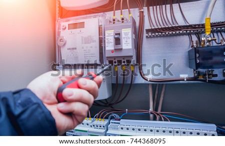 Electricians hands testing switches in electric box. Electrical panel with fuses and contactors. Background and texture