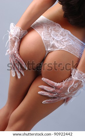perfect buttocks of elegant brunette woman in white sexy lingerie and gloves on isolated grey background.