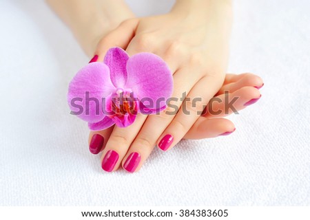 Beautiful hands with manicure and purple orchid flower