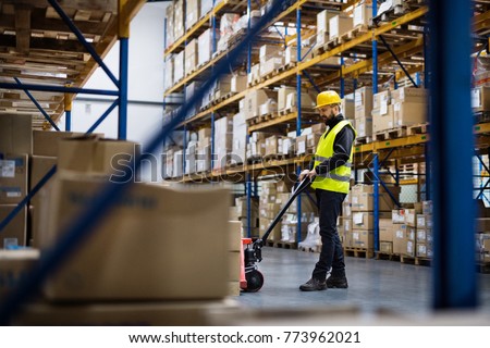 Male warehouse worker pulling a pallet truck.