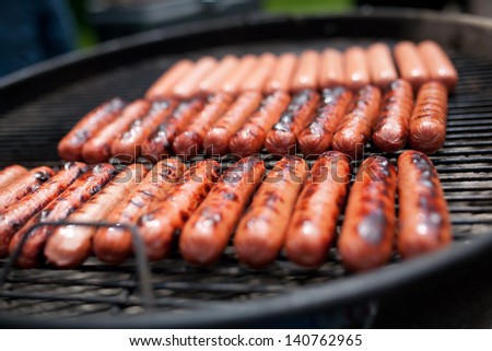 Several cooking hot dogs on a grill - stock photo