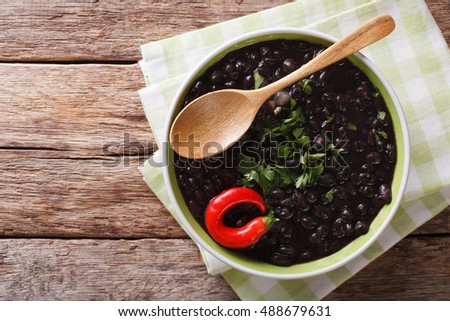 stewed black beans with spices and herbs in a bowl close-up on the table. Horizontal view from above