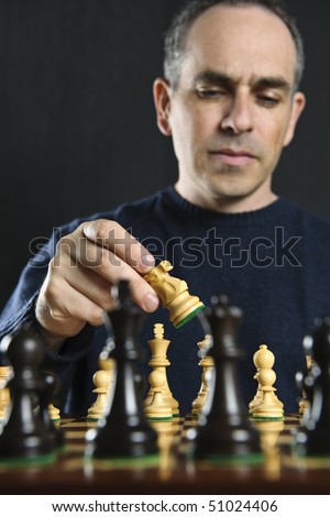 Man moving a chess piece on wooden chessboard