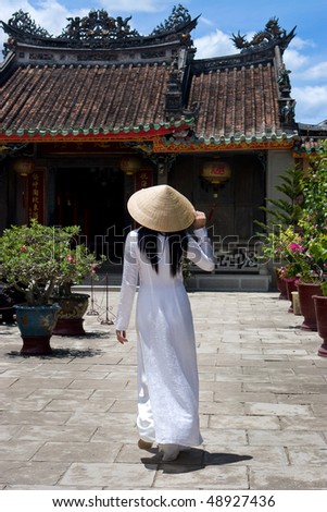 Vietnamese Woman wearing a Ao-Dai costume in front of a Temple