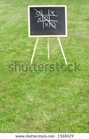 stock photo a chalkboard with tic tac toe game standing on the lawn space for copy 1368429