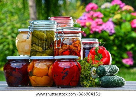 Jars of pickled vegetables and fruits in the garden. Marinated food.