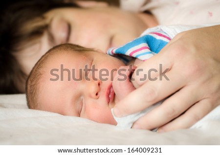 Newborn infant child resting next to mother after delivery at hospital