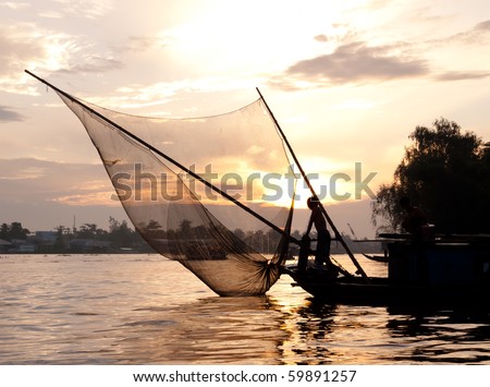 Fishing boat catching fish with fishnet at dusk on the Mekong river. Can Tho, Vietnam