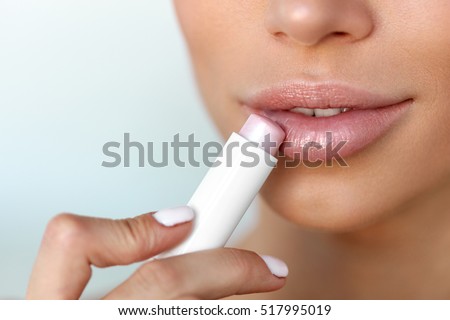 Lips Skin Care. Beautiful Woman Face With Sexy Full Lips Applying Hygienic Lip Balm, Lipcare Stick. Closeup Of Female Face With Soft Skin Putting Lip Protector Lipstick On. Beauty Cosmetics Concept