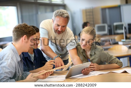 Teacher with group of students working on digital tablet