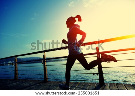 healthy lifestyle sports woman running on wooden boardwalk sunrise seaside 