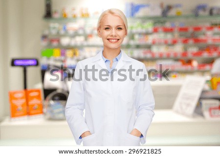 medicine, pharmacy, people, health care and pharmacology concept - happy young woman pharmacist over drugstore background