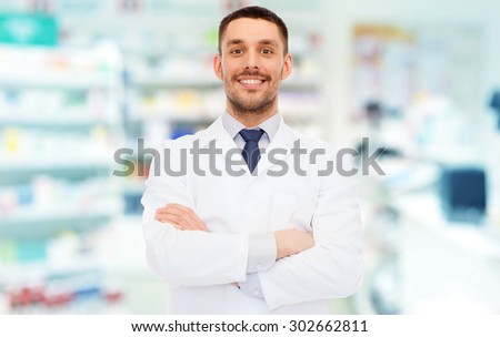 medicine, pharmacy, people, health care and pharmacology concept - smiling male pharmacist in white coat over drugstore background