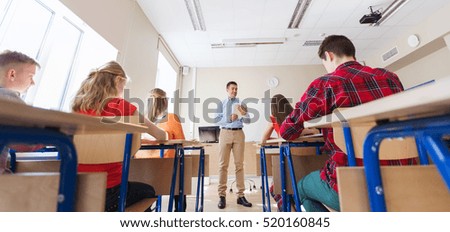 education, school, teaching, technology and people concept - group of happy students and teacher with tablet pc computer
