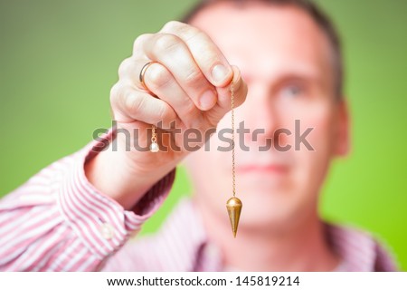Hand with pendulum, tool for dowsing.