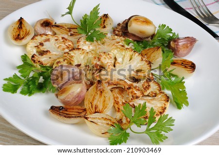 Warm appetizer of fried pieces of cauliflower with garlic and onion - stock photo