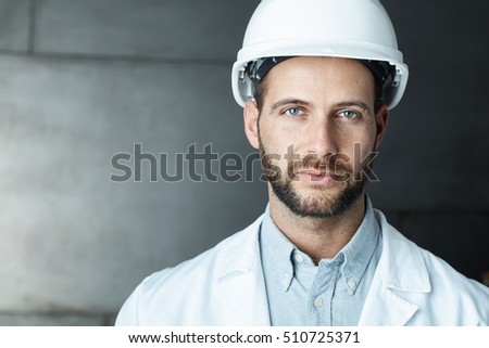 Portrait of confident young engineer wearing protective hardhat.