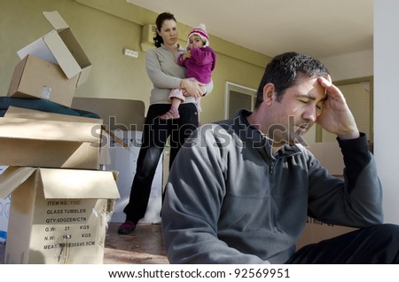 Young parents and their daughter stand beside cardboard boxes outside their home. Concept photo of  divorce, homelessness, eviction, unemployment, financial, marriage, family problems, family issues.