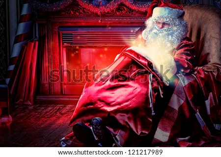 Santa Claus having a rest in a comfortable chair near the fireplace at home.