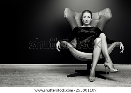 Black-and-white portrait of a stunning fashionable model sitting in a chair in Art Nouveau style. Business, elegant businesswoman. Interior, furniture.