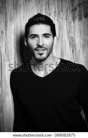 Black-and-white portrait of a positive young man smiling at camera. Men's beauty.