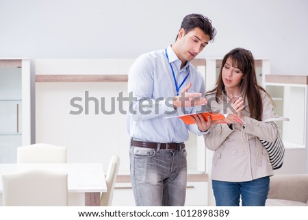 Salesman explaining to woman customer at furniture store