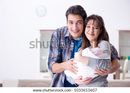 Young parents with their newborn baby near bed cot Young parents with their newborn baby near bed cot