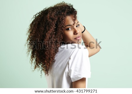 pretty black woman with a curly hair watching at camera from the back