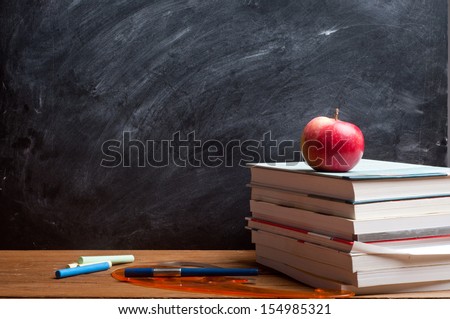 red apple resting on the book with chalk board as background