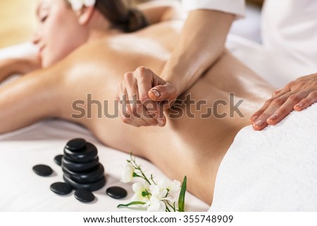 Young beautiful woman enjoying massage on the table at spa center