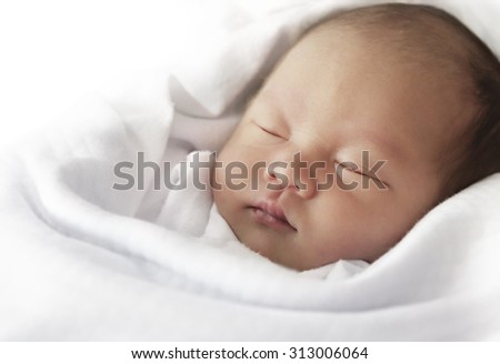 Asian newborn baby sleeping on white towel post processing with desaturated filter Asian newborn baby sleeping on white towel post processing with desaturated filter