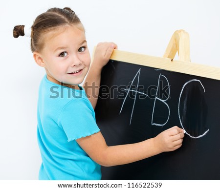 Cute little girl is showing letter E on the alphabet in preschool