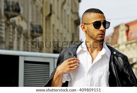 Fashion stylish young african man in sunglasses and black rock leather jacket.