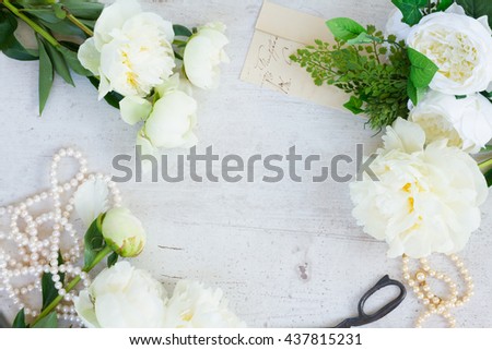 White fresh peony flowers with pearls jewellery on white wooden table frame with copy space