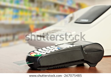 Close up of Credit Card Reader and Cash Register on background of Retail Shelves
