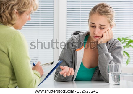 teenage girl suffering with depression in a conversation with therapist or psychologist teenage girl suffering with depression in a conversation with therapist or psychologist