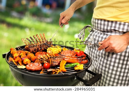 Man cooking meat on barbecue for family dinner