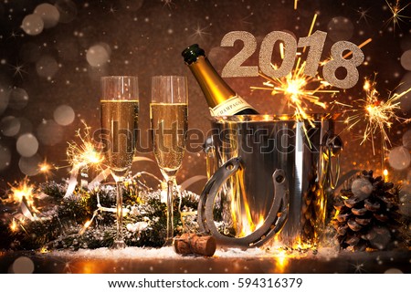 New Years Eve celebration background with pair of flutes and bottle of champagne in bucket and a horseshoe as lucky charm