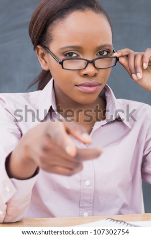 Strict black teacher pointing finger in a classroom