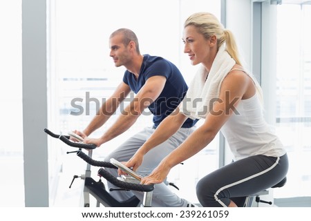 Determined fit young couple working on exercise bikes at the gym